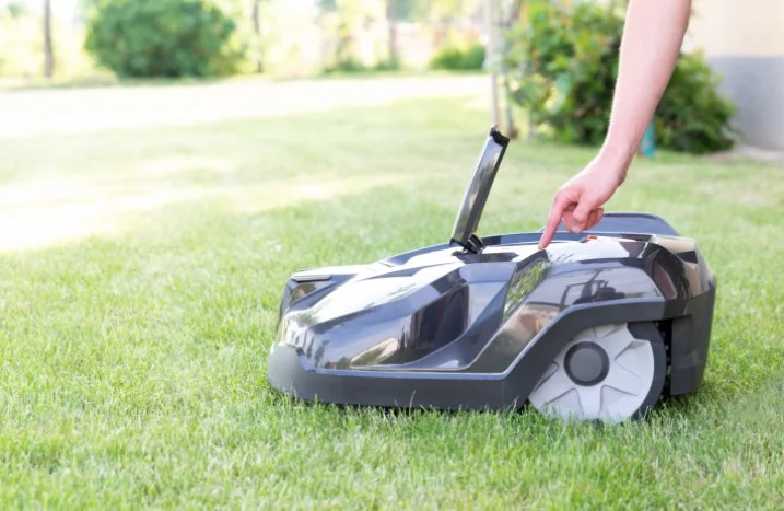 Person startet Mähroboter